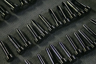 Rows of shiny metal components on a textured surface.