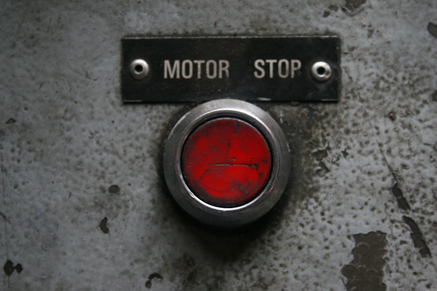 A red motor stop button on a metal control panel, representing a circuit breaker that halts a runaway agent loop