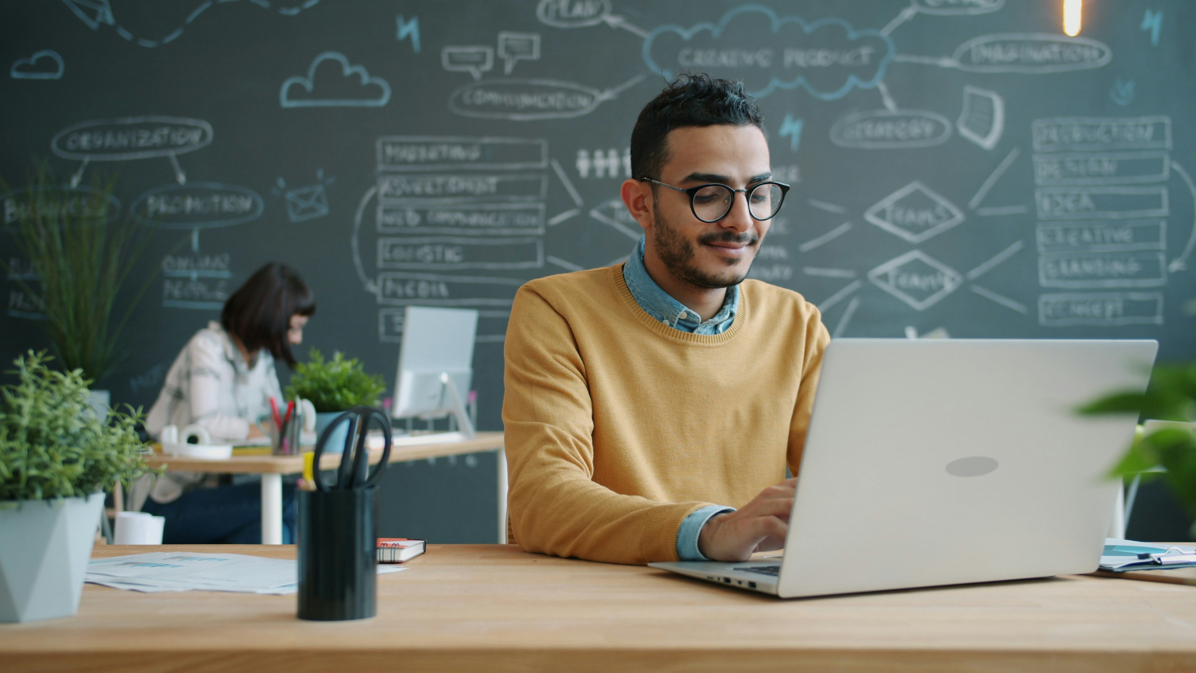 Portrait of Afro-American man working with laptop in open space office typing enjoying job