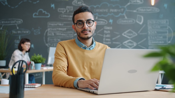 Man with glasses working on laptop in office