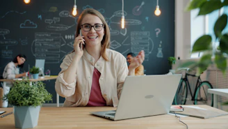 Smiling woman talking on phone in modern office.