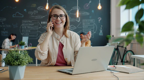 Smiling woman talking on phone in modern office.