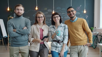Four smiling people standing in a modern office.