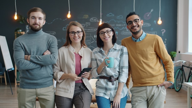 Four smiling people standing in a modern office.