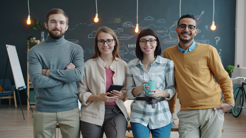 A diverse team of colleagues, men and women, standing together in the office