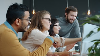Diverse team collaborating around a computer screen.