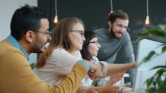 Diverse team collaborating around a computer screen.