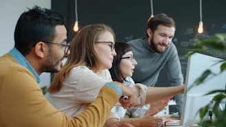 Diverse team collaborating around a computer screen