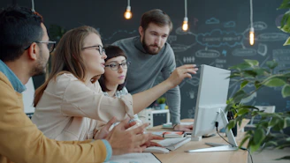Team collaborating around a computer in an office.