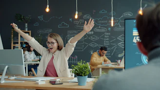 Woman celebrating success at her office desk.