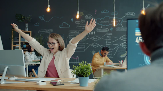 Woman celebrating success at her office desk.