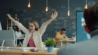 Woman celebrating success at her office desk.