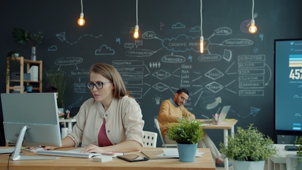 Woman working on computer in modern office with chalkboard.