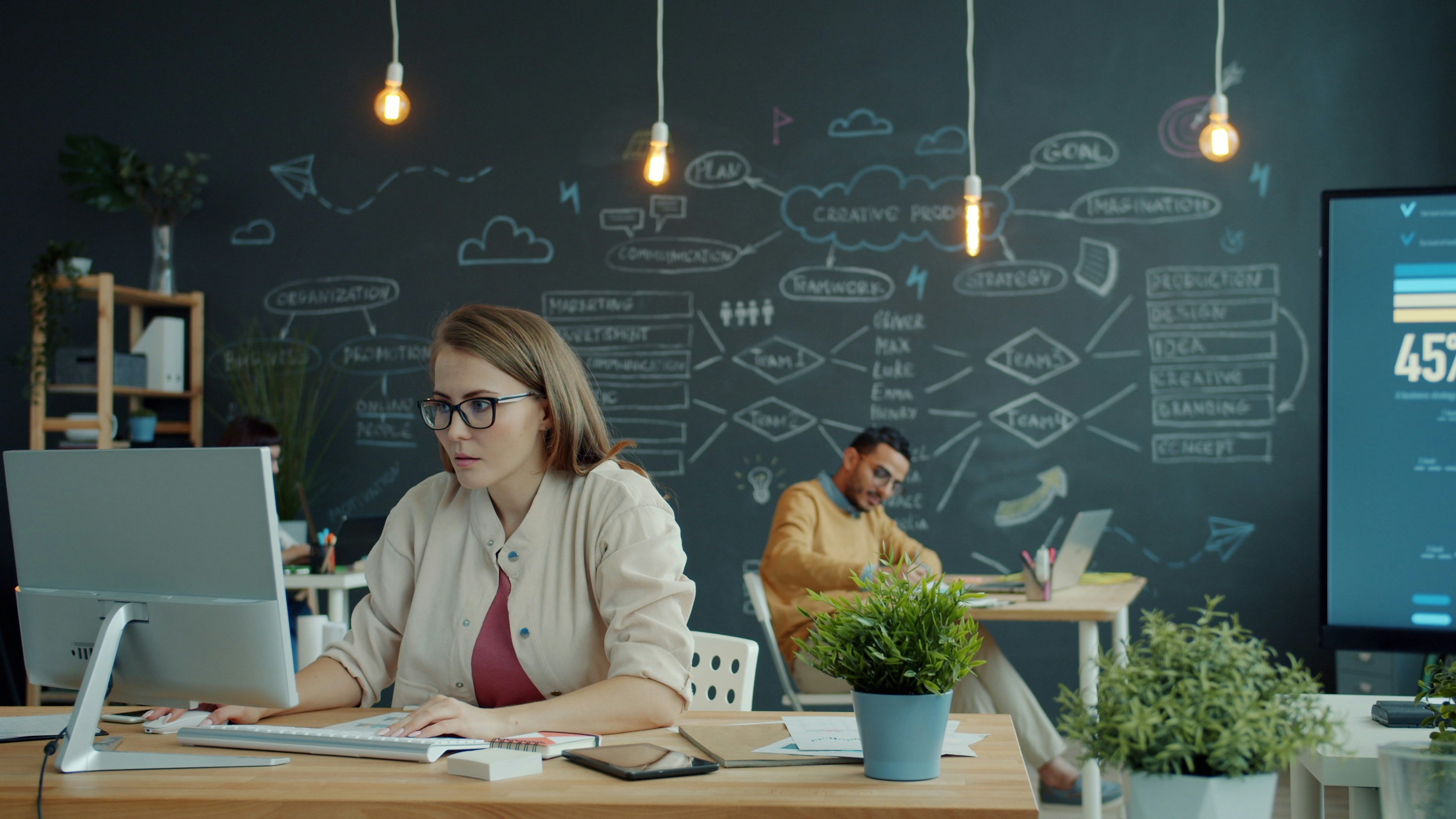 data analyst working on multiple computer monitors in modern office