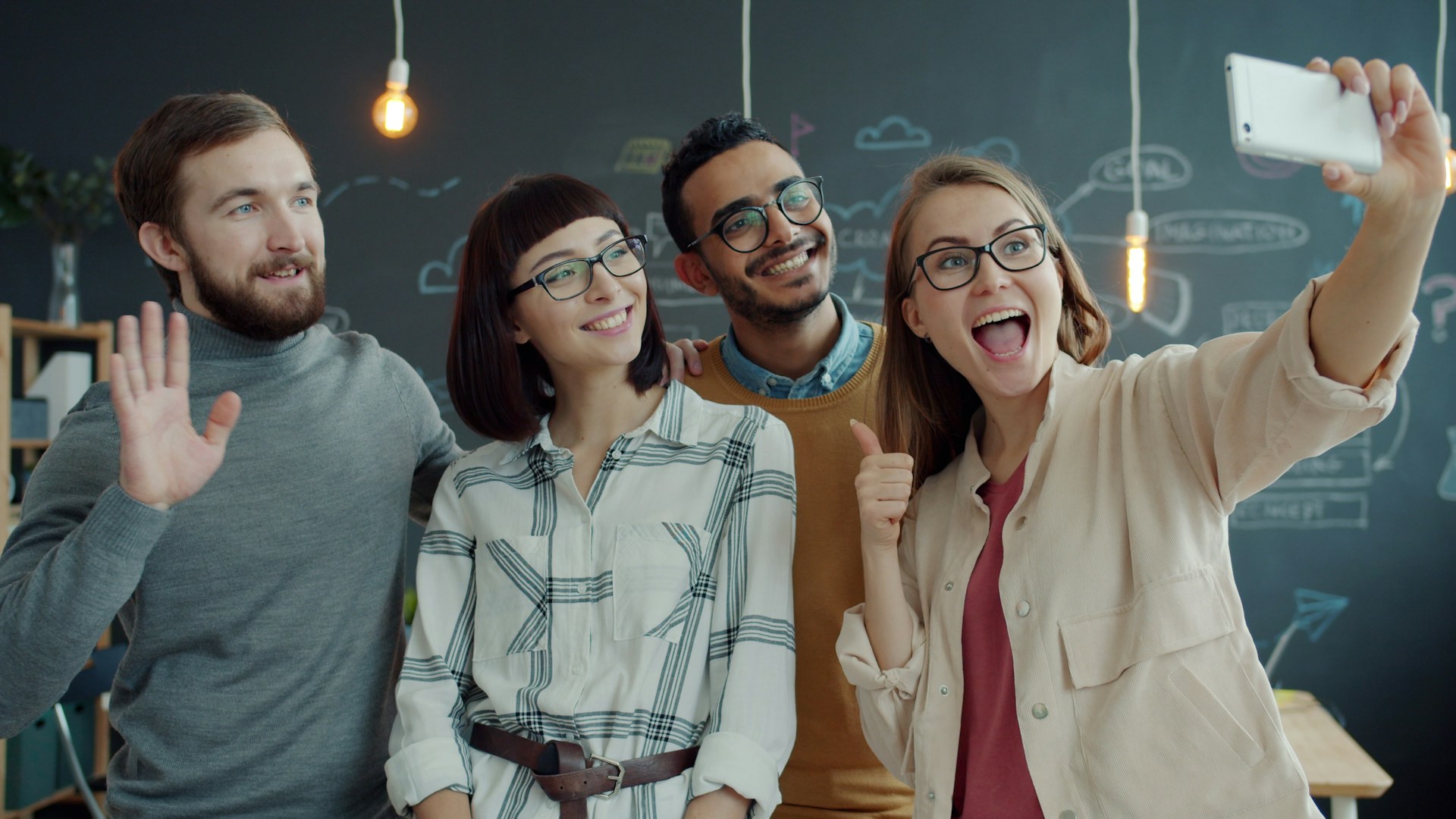Four friends taking a selfie in a modern office.