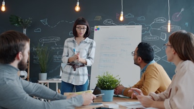 Woman presents to colleagues at a whiteboard meeting.
