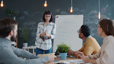 Woman presents to colleagues at a whiteboard meeting.