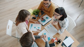 Four people collaborating around a table with documents.