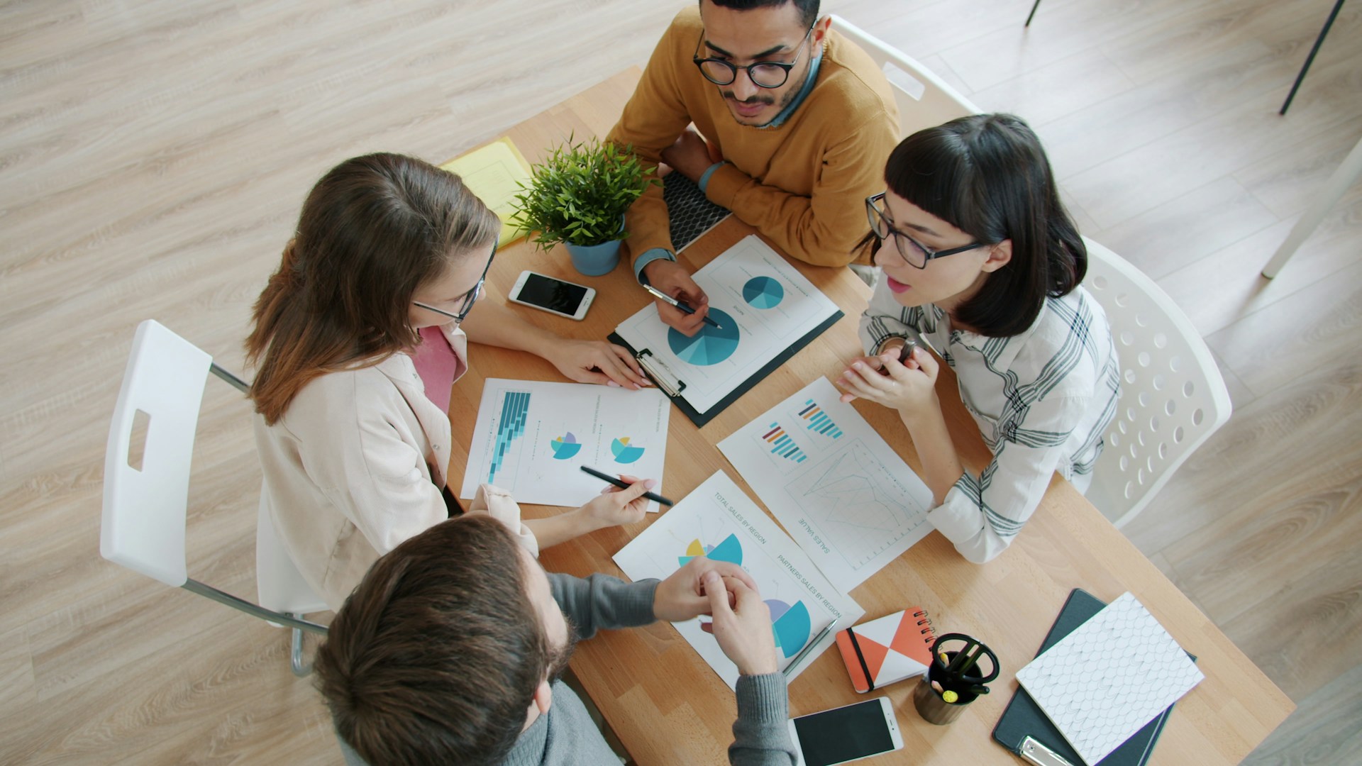 Four people collaborating around a table with documents.