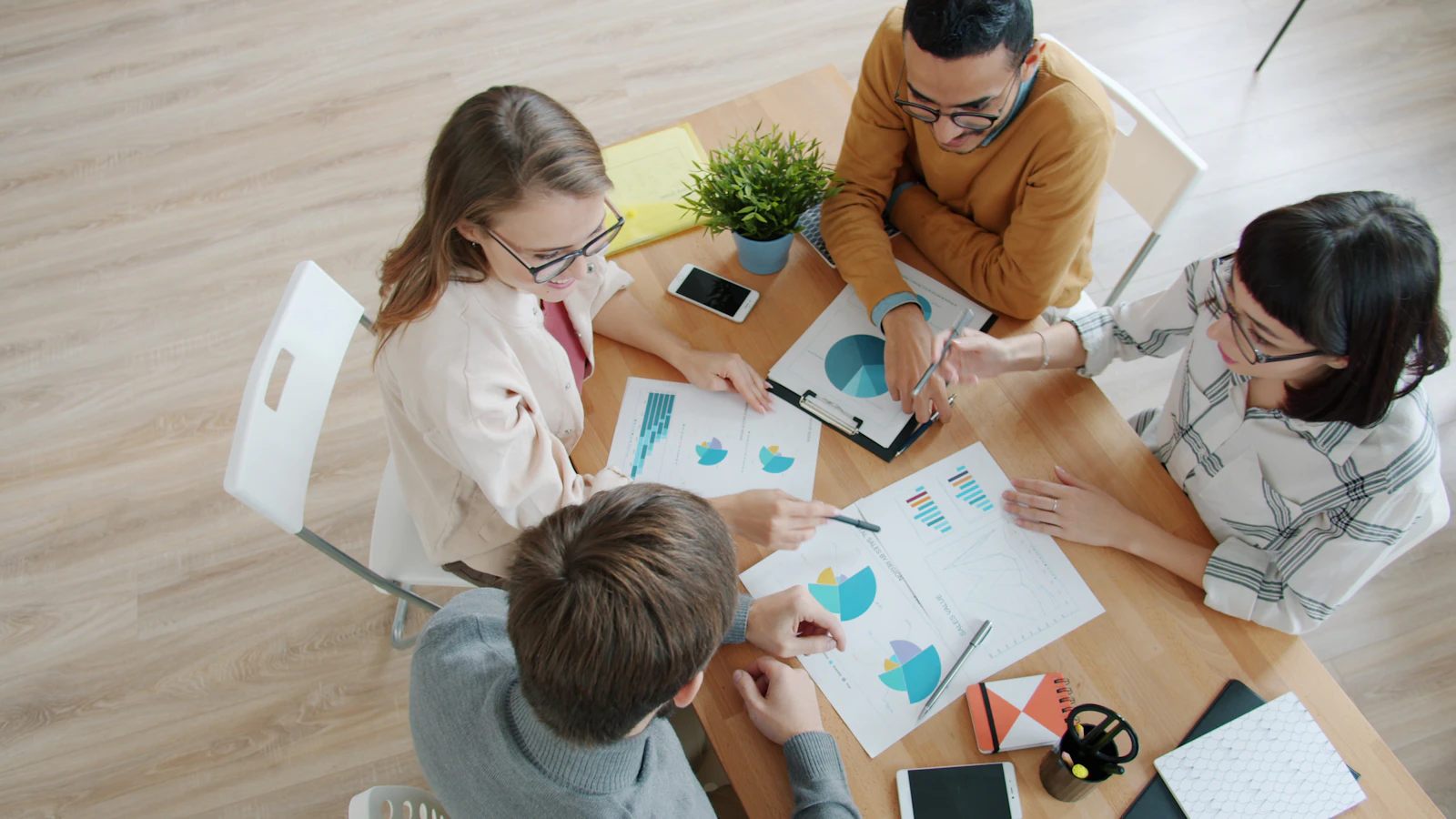 Team of professionals collaborating around a table with strategy charts and graphs in a modern office setting