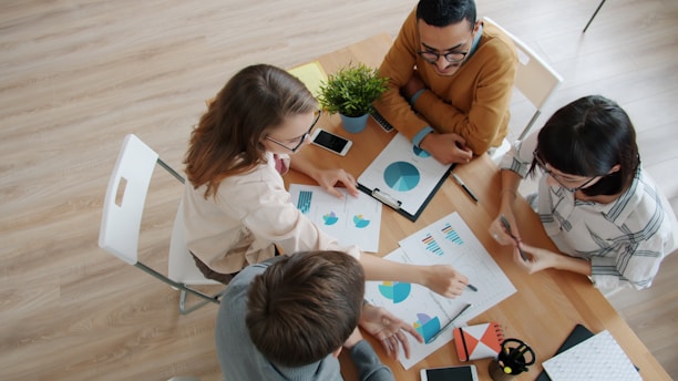 Diverse team collaborating around a table with charts.