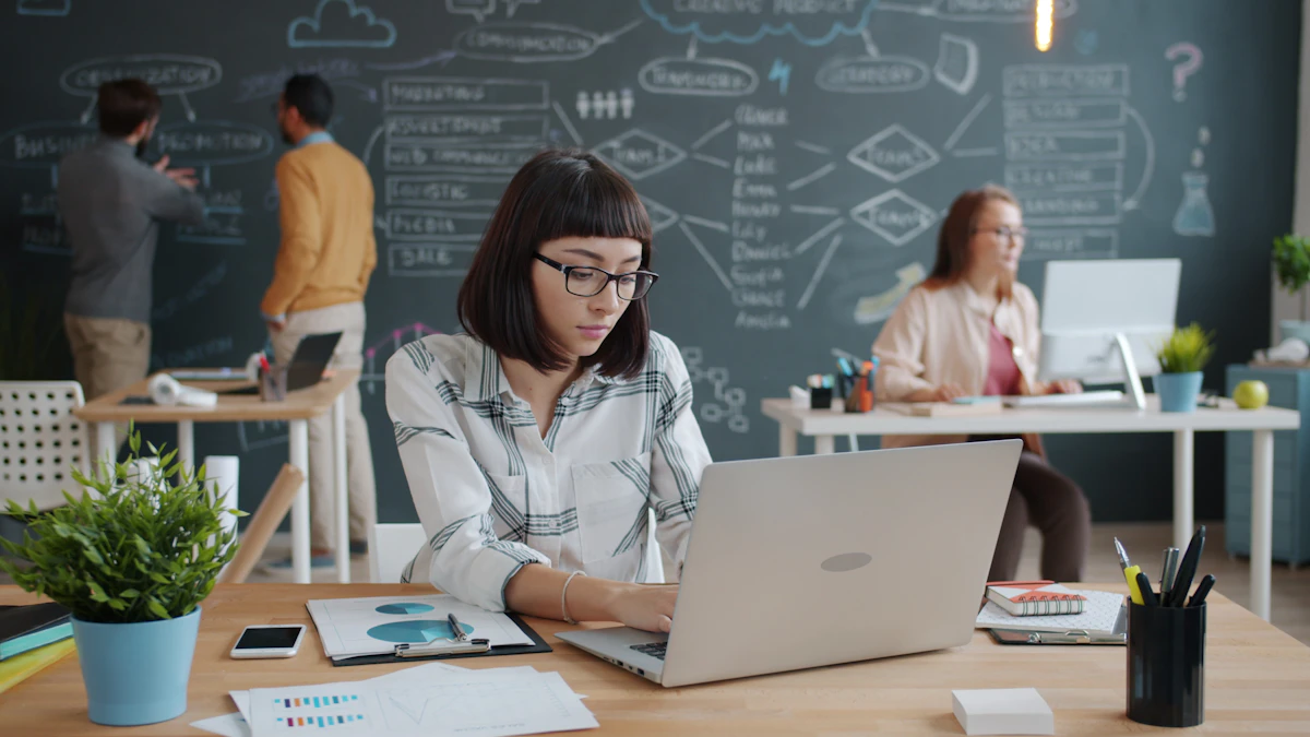 Professional working on a laptop with the team in the background