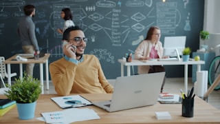 Man talking on phone in modern office with team
