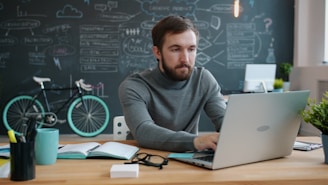 Man working on laptop in office with bicycle.