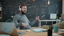 Man with headphones playing air guitar at desk