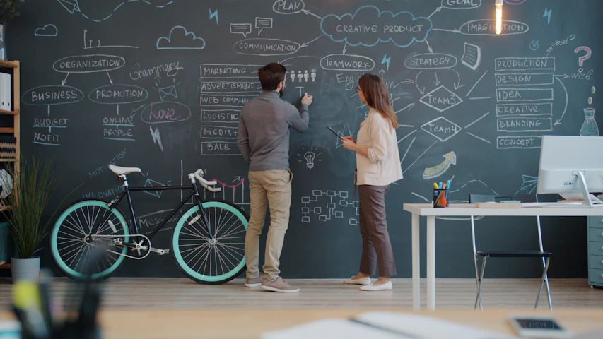Two people drawing on a chalkboard wall
