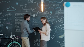 Two people discussing a business plan on chalkboard.