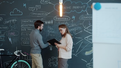Two people discussing a business plan on chalkboard.