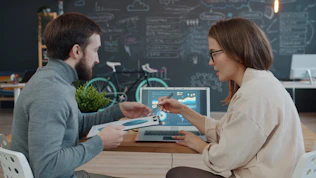 Two colleagues reviewing data on a laptop