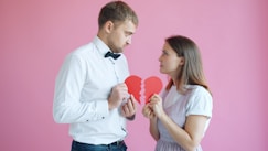Couple holding broken heart halves on pink background