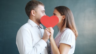Couple holding red heart obscuring faces