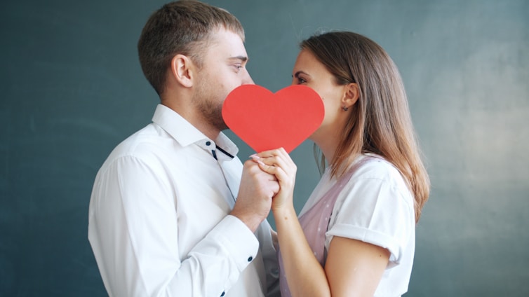 Couple holding red heart obscuring faces