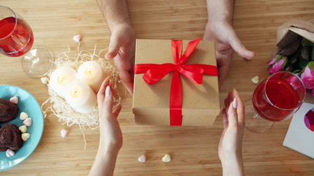 Hands exchanging a gift box with red ribbon