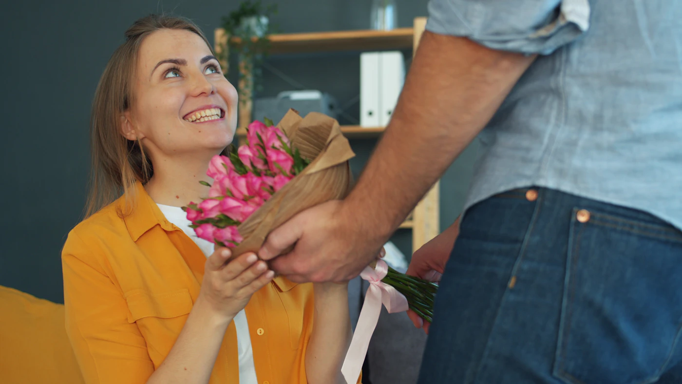 Woman receiving pink flowers as a six month anniversary gift