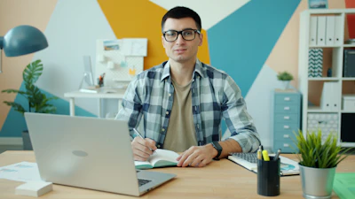 Man working at a desk with laptop and notebook.