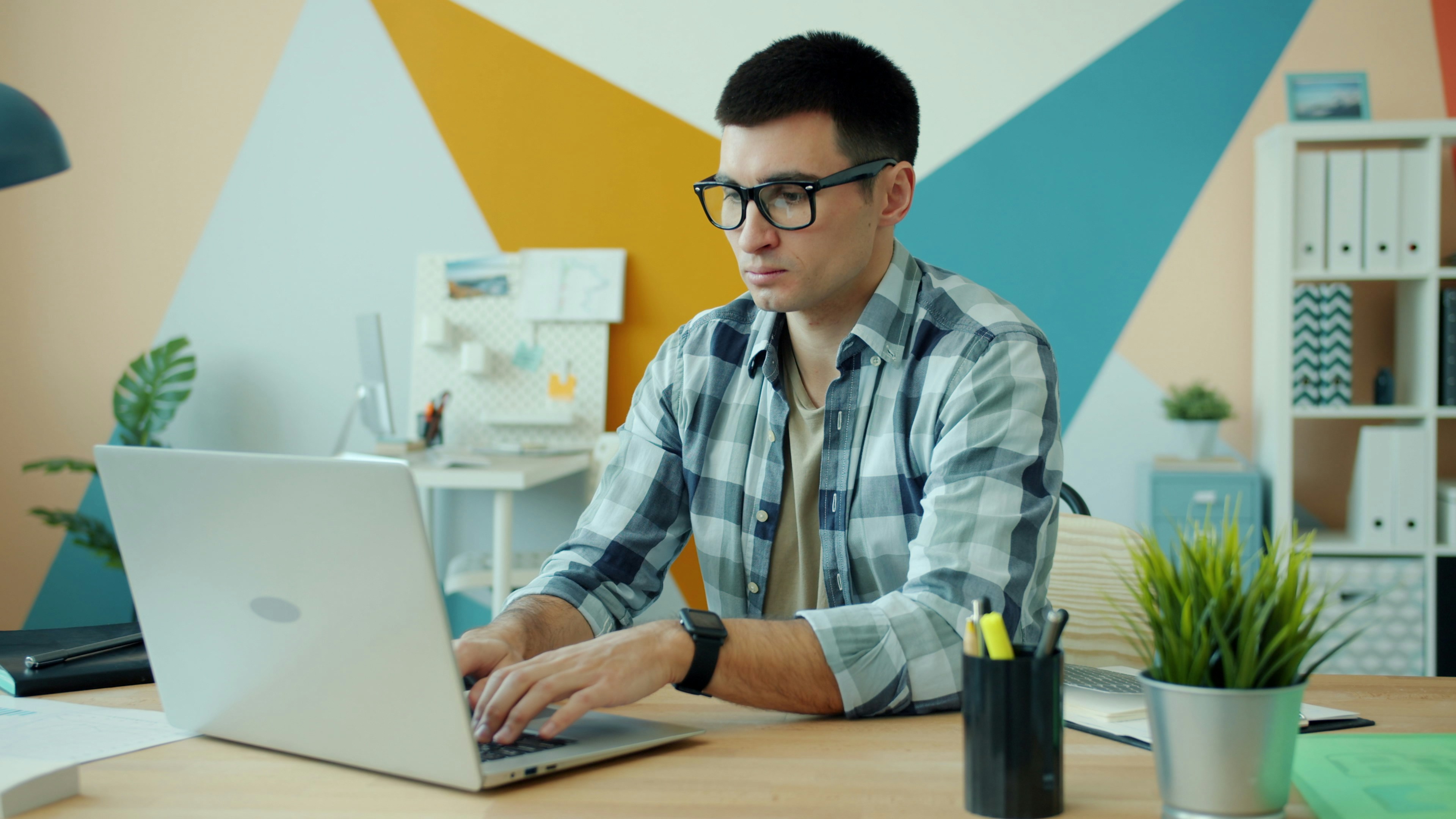 Man working on a laptop in a colorful office.