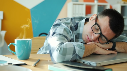 Man sleeping at desk with coffee nearby