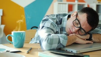 Man sleeping at desk with coffee nearby