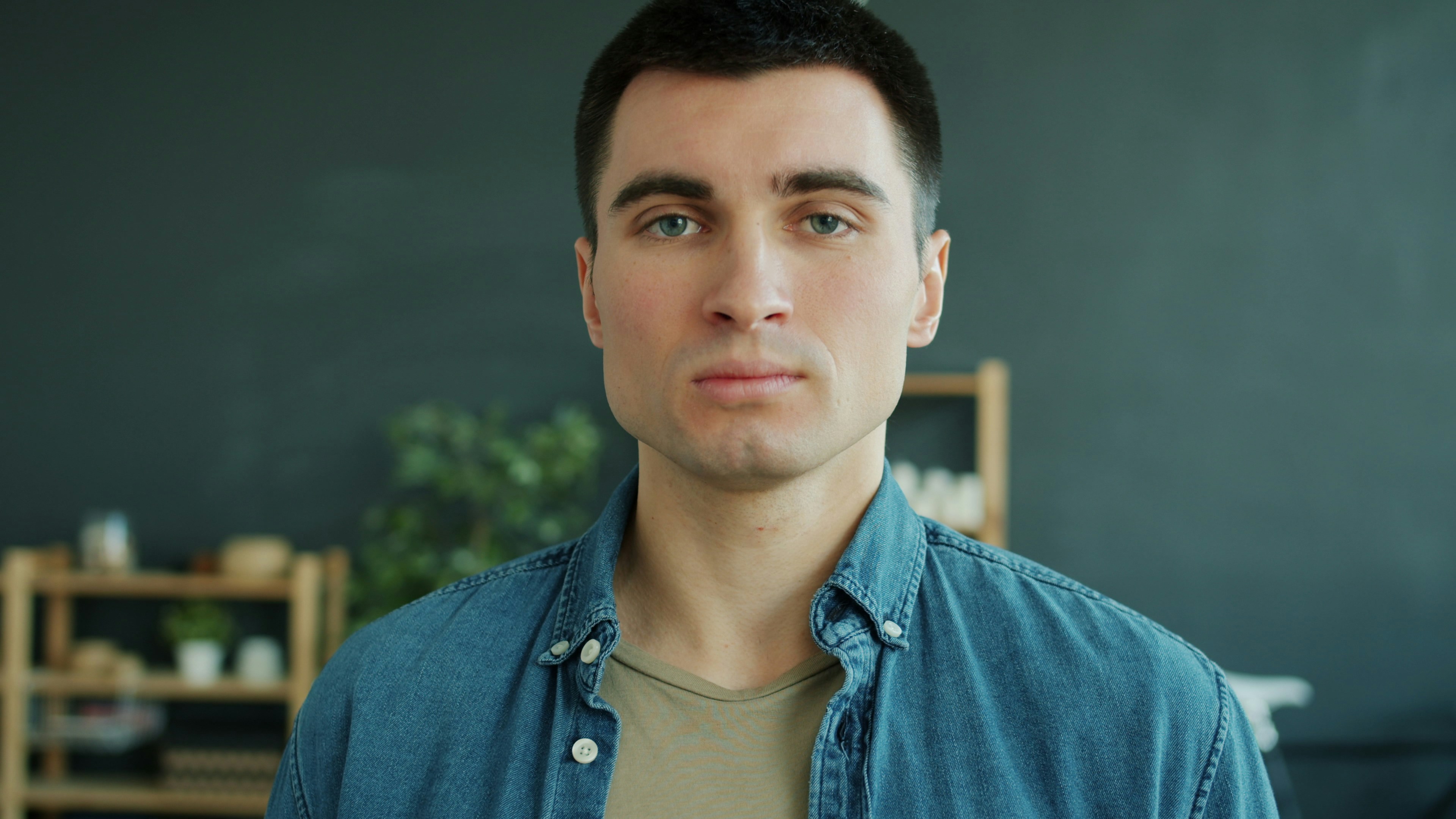Um homem de camisa jeans olha para frente.