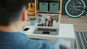 Man video calls two smiling women on laptop.
