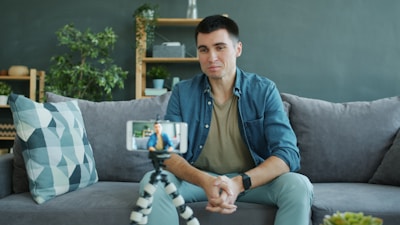 Man sitting on couch recording video on phone