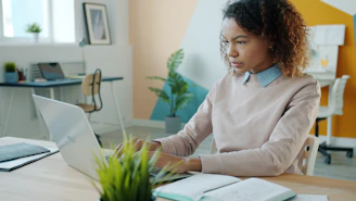 A young woman working on a laptop in an office.