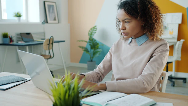 A young woman working on a laptop in an office.