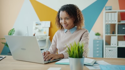 Young woman working on a laptop at a desk.