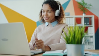 Young woman wearing headphones works on laptop.