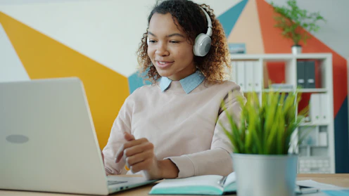 Young woman wearing headphones works on laptop.